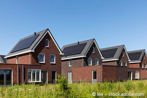 4 identische Backsteinhäuser in einem Neubaugebiet mit Solarpaneelen auf den Schrägdächern