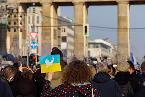 Woman with a poster of the Ukrainian flag and other people on the street